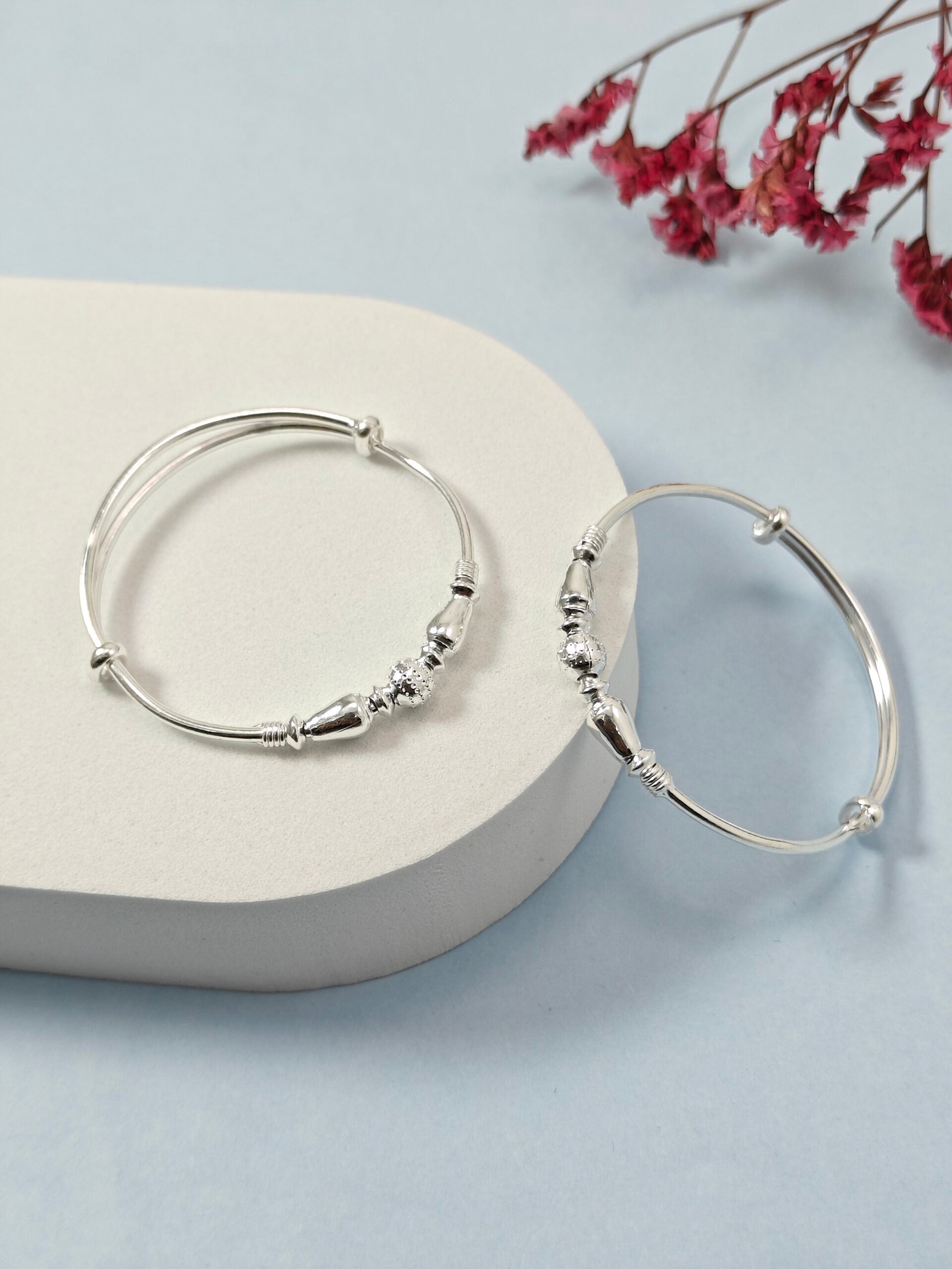 Silver hoop earrings on a light gray surface with pink flowers in the background